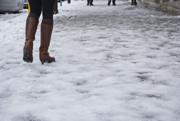 Woman with brown leather boots walks on icy street