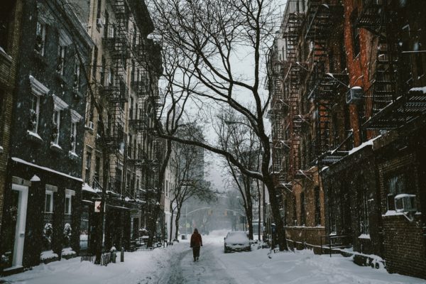 Person walks between two city buildings on snowy street