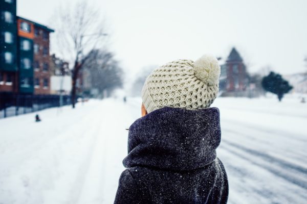 Child in winter coat and hat outside in snowy scene