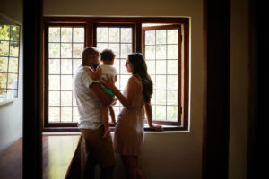 Shot of a young family looking out of the window in their new home